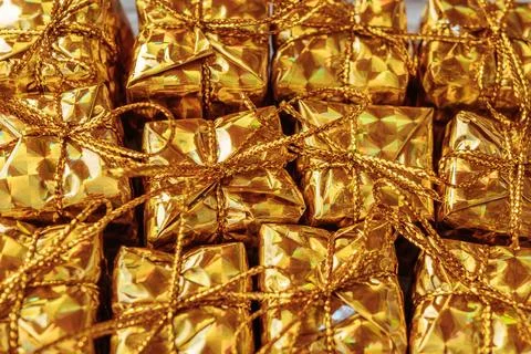 A full-frame close-up of several shiny gold gift boxes tied with gold. Stockfoto's