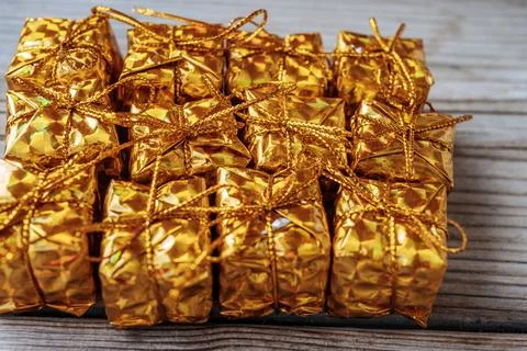 A full-frame close-up of several shiny gold gift boxes tied with gold. Stock Photos