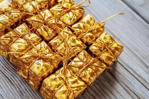 A full-frame close-up of several shiny gold gift boxes tied with gold. Stock Photos