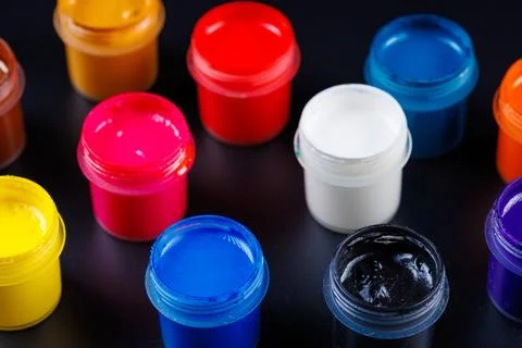 Full-frame close-up view d of opened small gouache paint jars on black surface Stock Photos