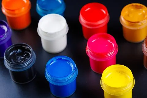 Full-frame close-up view d of opened small gouache paint jars on black surface Stock Photos