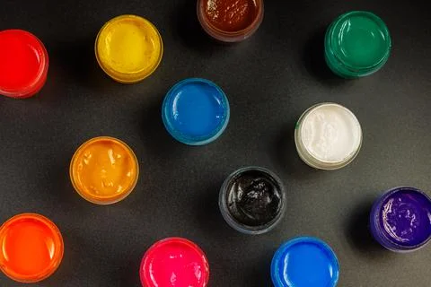 Full-frame close-up view d of opened small gouache paint jars on black surface Stock Photos