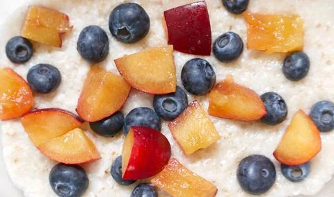 Full frame healthy breakfast background with porridge blueberries and plums Stock Photos