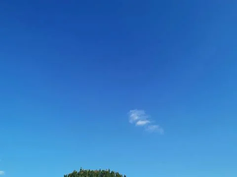 Full frame image of blue sky with simple cloud formation and part of tree Stock Photos