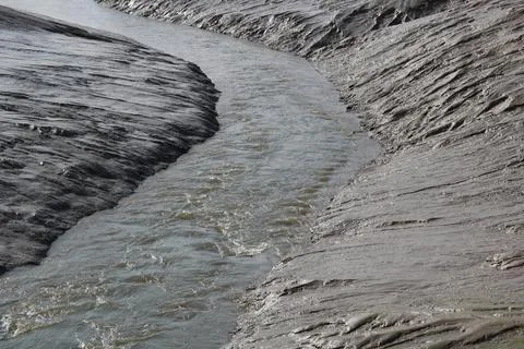 Full frame image of mud flat with small river running through Stock Photos