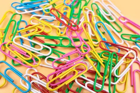 Full Frame of MultiColored Paperclips Isolated on a Cheerful Orange Beige Stock Photos