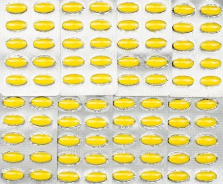 Full frame of oval yellow tablets pills in blister packs. Yellow pills patter Stock-Fotos