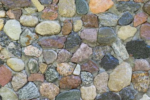 Full frame of shining different shape pebbles stacked into a cement wall Foto stock