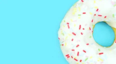 Full frame of white doughnut with sprinkles on blue background. Flat lay, top Stock Photos