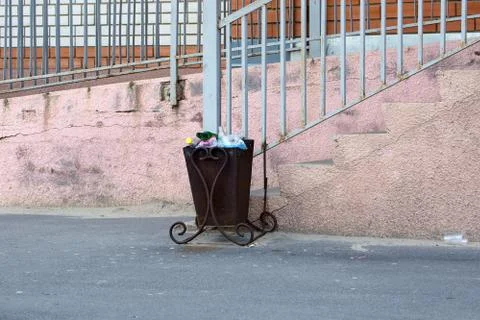 Full garbage can in the background of a house outdoors Stock Photos