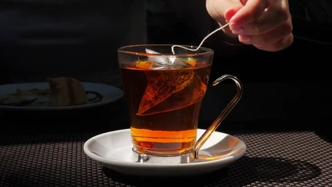 Full glass of boiling hot water, tea bag brew up, woman move it up and down Stock Footage 103182653