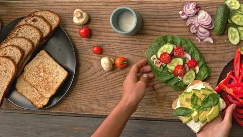 Full grain bread with avocado and green vegetables on the wood board Video stock 160850668