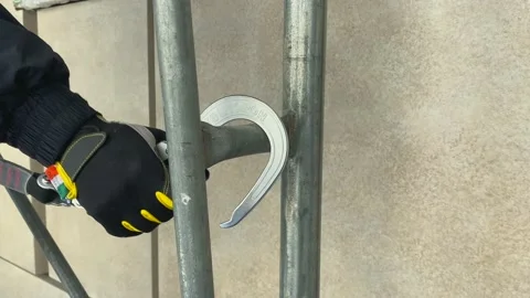 Full harness, the worker on a scaffold fixes the safety hook for safe work. Stock Footage 150208788
