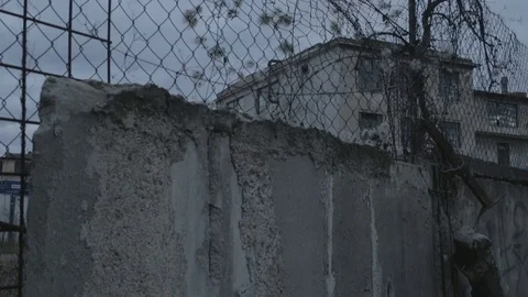 Full HD EXT DUSK pan old abandoned building behind a damaged wall Stock Footage 73110213