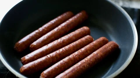 Full HD Female Hand Placing Sausages on Skillet Stock-Footage 315585993