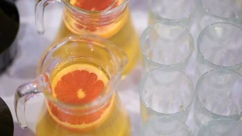 Full jars of orange juice and mulled wine and empty glasses for juice on tabel Stock Footage 99701664