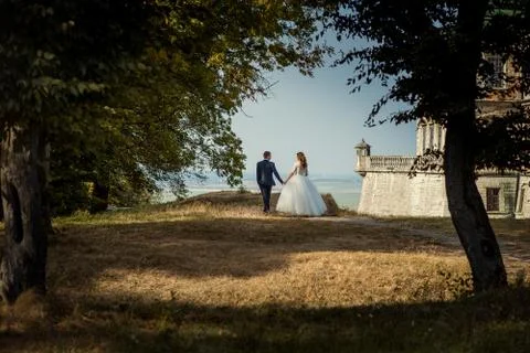 Full-length back view of the amazing newlywed couple holding hands and enjoying Stock Photos