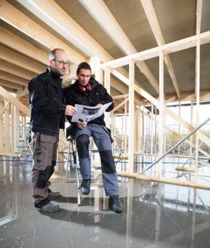 Full Length Of Carpenters With Plan At Construction Site Stock Photos