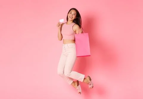 Full length of dreamy and carefree asian girl on shopping, jumping upbeat and Stock Photos