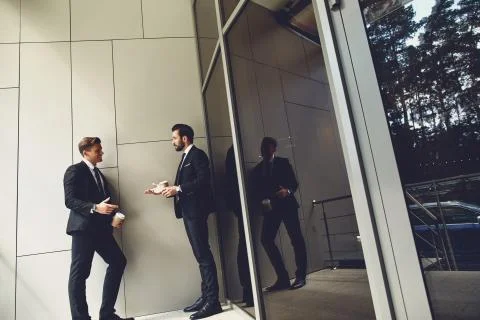 Full length of friendly men talking outdoors and smiling Stock Photos
