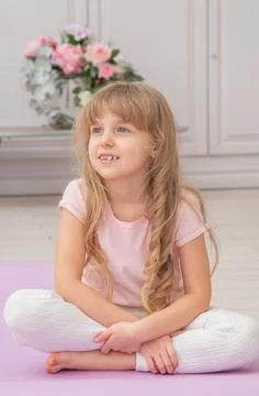 Full length front view cute little preschool girl sitting on on yoga mat Foto stock