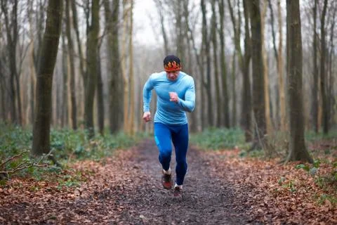 Full length front view of runner on tree lined path looking down Stock Photos