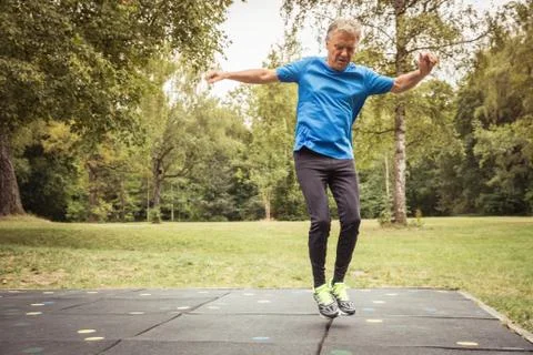 Full length front view of senior man in park jumping in mid air Fotos Stock
