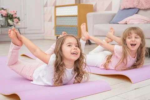 Full length front view smiling cute girls sitting on on yoga mat Stock Photos