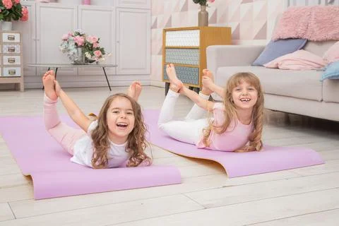 Full length front view smiling cute girls sitting on on yoga mat Stock Photos