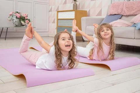 Full length front view smiling cute girls sitting on on yoga mat Stock Photos