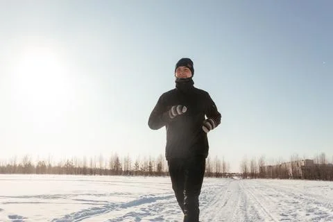 Full length of a happy middle-aged athlete running in nature on a snowy winter Stock Photos