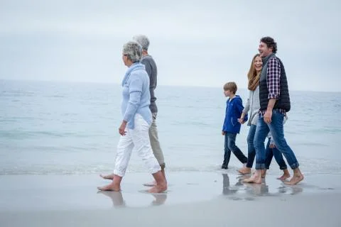 Full length of happy multi-generation family walking at sea shore 库存照片