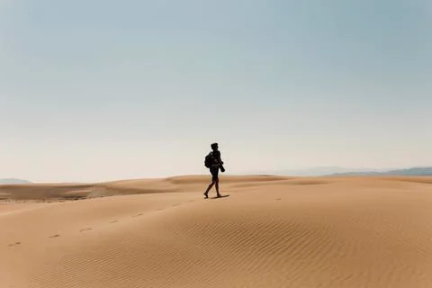 Full length of hiker with backpack exploring desert against sky Stock Photos