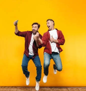 Full length image of two handsome men taking selfie photo on cellphone Stock Photos