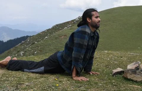 Full length of a long haired handsome young Indian man doing Bhujangasana  Stock Photos