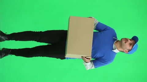 Full-length male courier holding a box on a green background Stock Footage 261384053