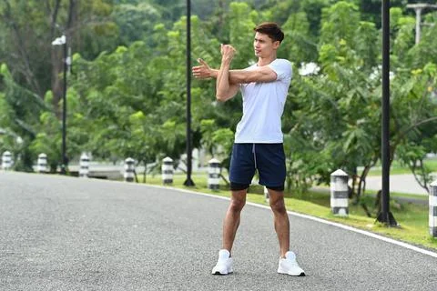 Full length man warming up, stretching her arms before morning workout. Fitness Stock Photos