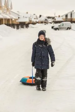 Full length portrait of boy pulling inflatable ring in snow Stock Photos