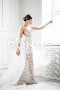 A full length portrait of a charming lady in a wedding dress posing indoor. W Stock Photos