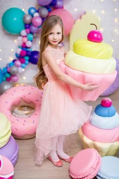 Full length portrait of cute little girl posing with big cupcake and giant pa Фото