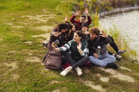 Full-length portrait of group of friends having nice picnic, taking selfie near Stock Photos