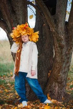 Full-length portrait of a red-haired girl in a large yellow maple leaf wrea.. Photos