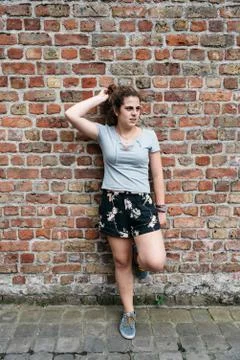 Full length portrait of smiling expression young adult woman leaning agains.. Stock Photos