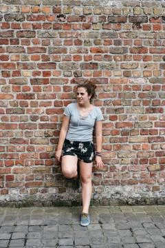 Full length portrait of smiling expression young adult woman leaning agains.. Stock Photos