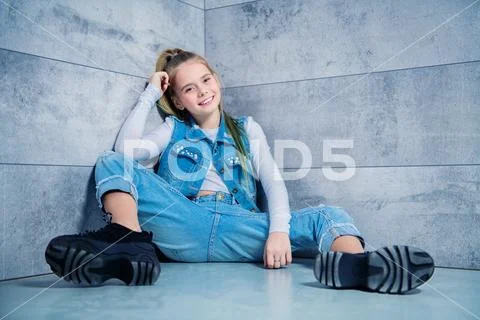 A full length portrait of a young girl posing in the corner in the studio. Be Stock Photos