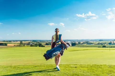 Full length rear view of an active woman carrying a blue stand bag Stock Photos
