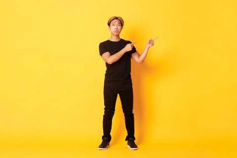 Full-length of sad and miserable asian guy in black clothes, pouting, pointing Fotos Stock