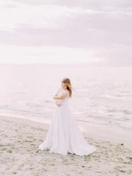 The full-length side portrait of the bride in the long wedding dress at the Stock Photos