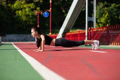 Full length side view of a beautiful athletic woman doing push ups outdoor Stock Photos