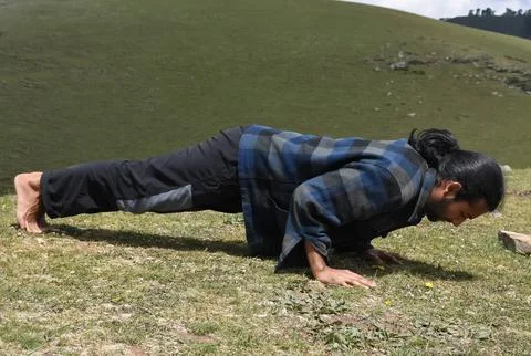 Full length side view of a handsome long haired Indian young man doing push ups  Stock Photos